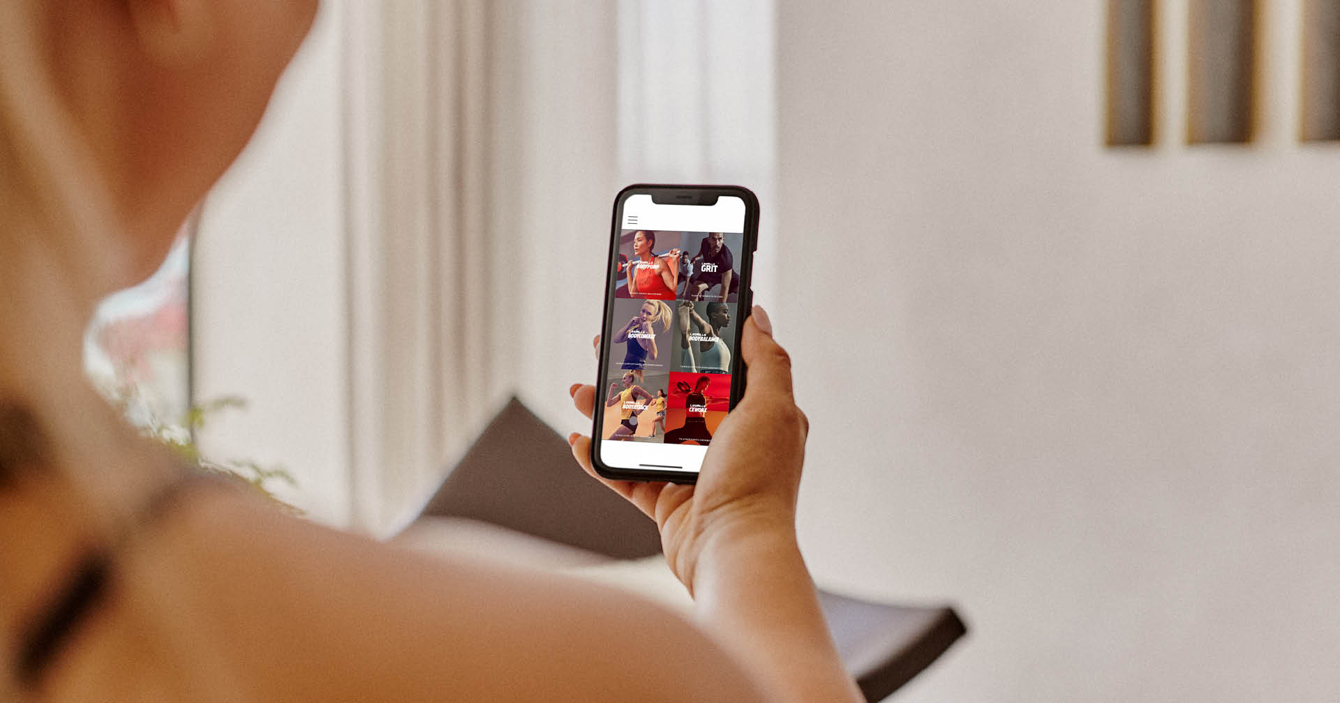 Frau hält Handy mit digitalen Fitnessangeboten