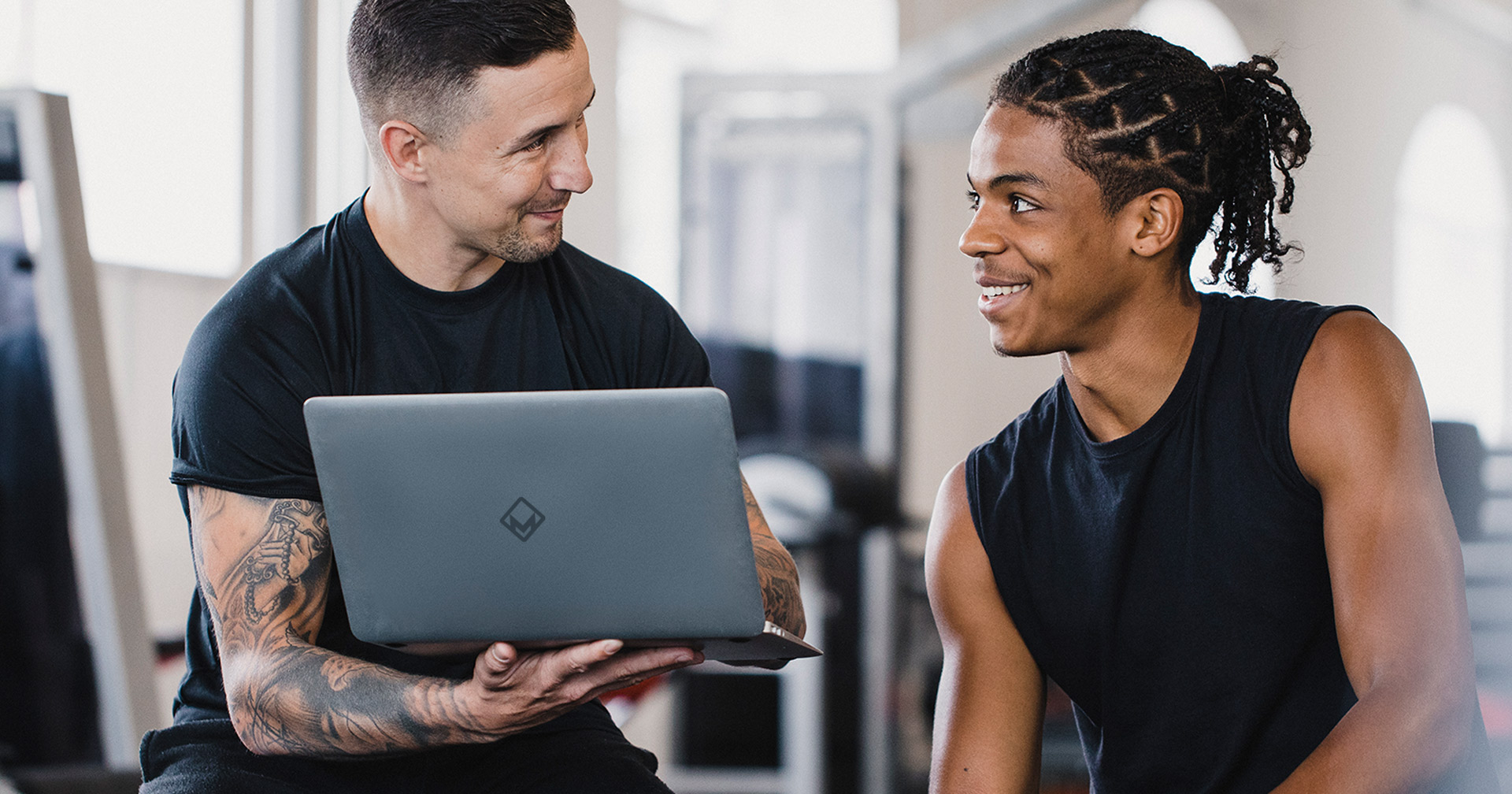 Fitnesstrainer zeigt Fitnessstudiomitglied seinen Fortschritt in der Magicline-Software