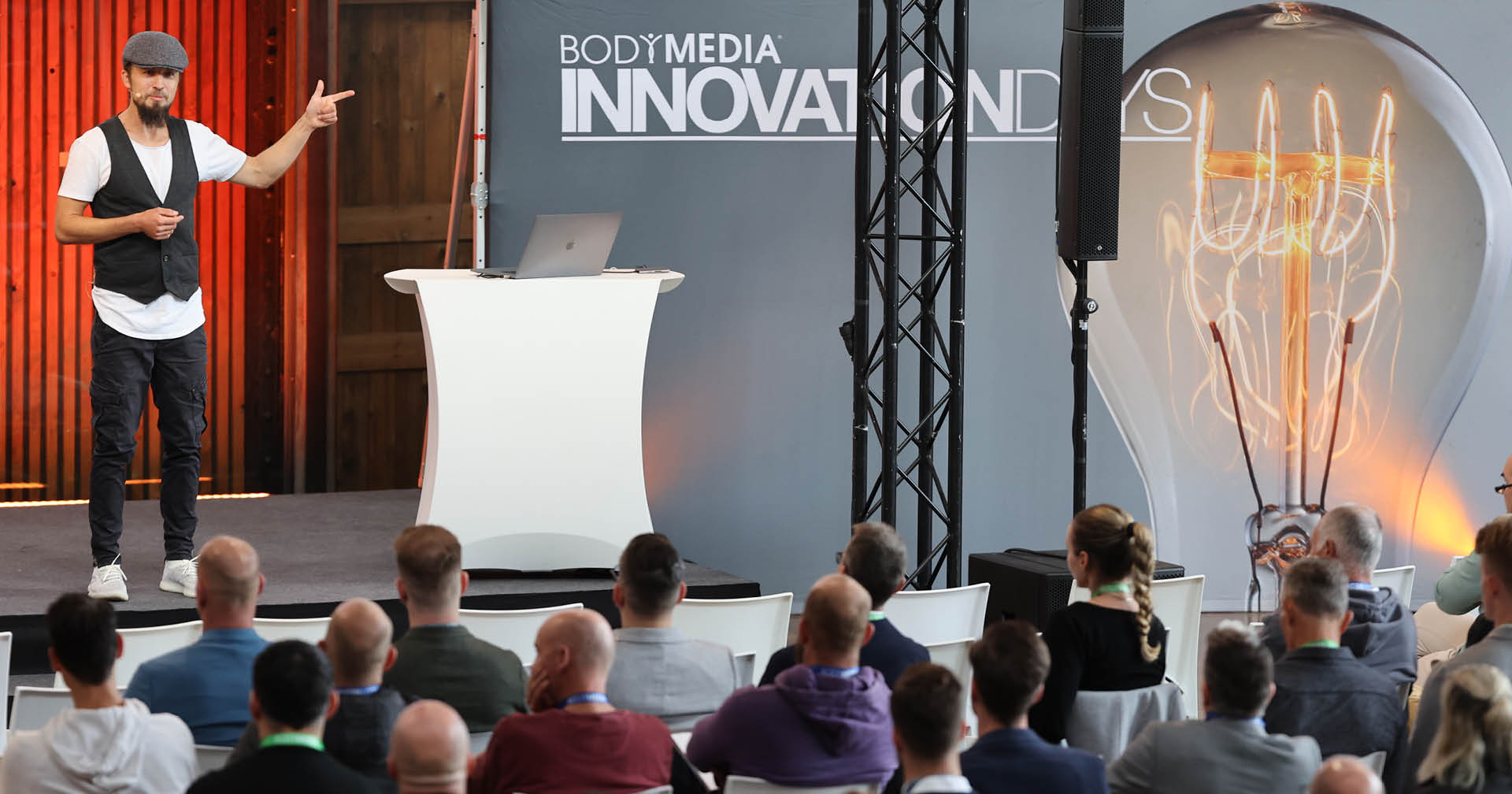 Tobias Conrad steht vor einem Publikum auf der Bühne als Moderator auf den BODYMEDIA Innovation Days