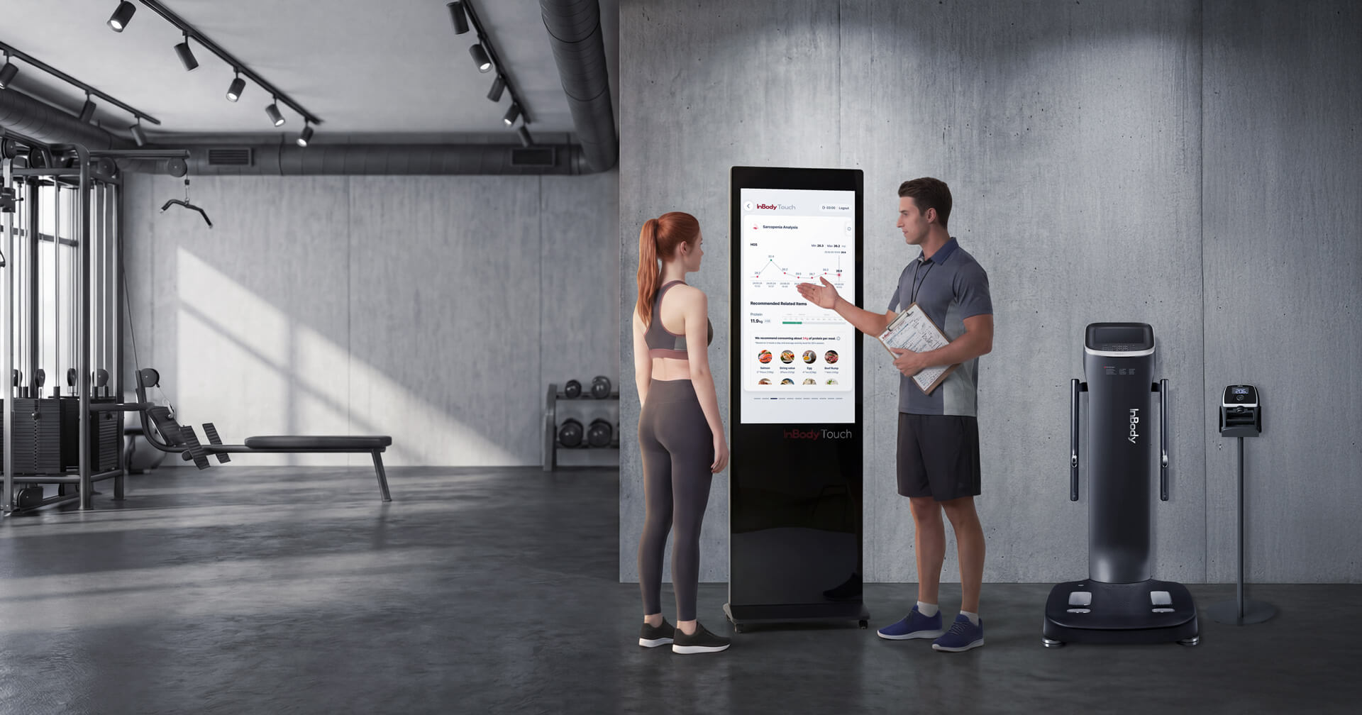 Ein Trainer mit Klemmbrett erklärt einer Sportlerin in einem modern gestalteten Fitnessstudio mit Sichtbetonwänden die Auswertungen auf einem „InBody Touch“-Terminal. Rechts daneben stehen eine professionelle InBody-Körperanalysewaage und ein InGrip-Messgerät auf einem Ständer.