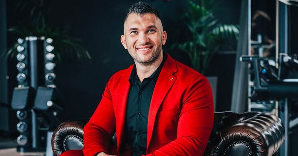 Eugen Leibman sitzt im roten Jacket auf Ledersessel und lacht in die Kamera