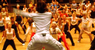 Trainerin führt vor Sportlern eine dynamische Bewegung aus