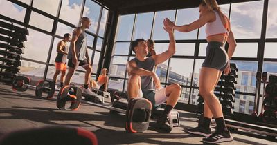 Sportler geben sich High Fives in einem Gym mit Fenstern im Hintergrund und dem Blick auf eine Stadt