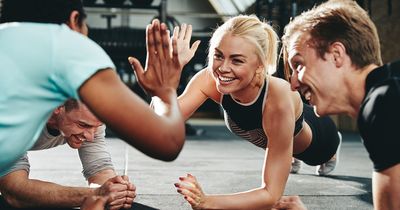 Frau und drei Männer in Plank-Position im Fitnessstudio