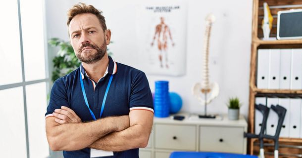 Ärgerlicher Physiotherapeut steht vor seiner Behandlungsbank