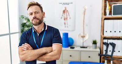 Ärgerlicher Physiotherapeut steht vor seiner Behandlungsbank