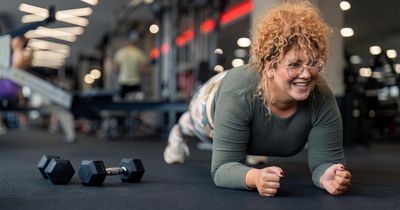 Übergewichtige Frau trainiert Plank im Gym