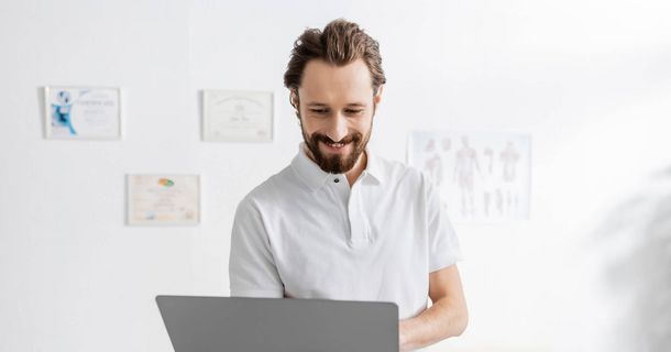 Physiotherapeut mit Laptop in seiner Physiopraxis