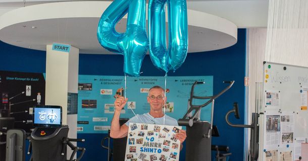 Franko Rinner steht im Studio mit Plakat und 40-Luftballon