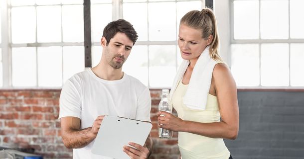 Trainer zeigt einem Fitnessstudiomitglied etwas an einem Tablet