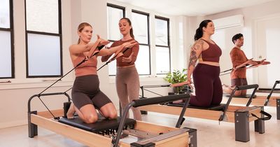 Sportler führen Pilatesübungen aus, während eine Trainerin Korrekturen vornimmt