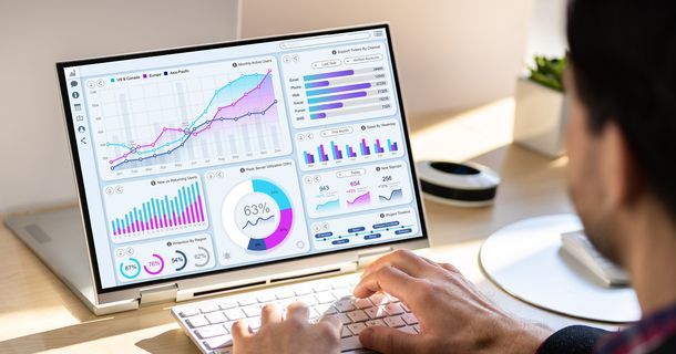 Laptopbildschirm mit Charts vor dem ein Mann sitzt