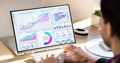 Laptopbildschirm mit Charts vor dem ein Mann sitzt