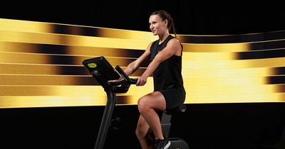 Frau trainiert auf Technogym-Bike vor gelber LED-Wand