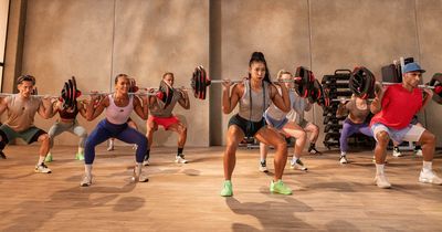 Groupfitnesskurs. Teilnehmer machen Squats mit Langhantet Les Mills launcht BODYPUMP HEAVY