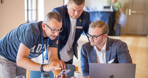 3 Männer beim Netzwerk schauen auf den Laptop und auf das Handy und netzwerken 