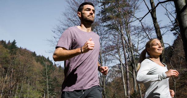 Ein Mann und eine Frau joggen gemeinsam durch den Wald 