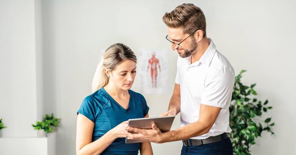 Therapeut zeigt einer Patientin etwas auf einem Tablet