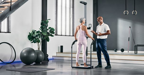 Frau steht auf der seca TRU, daneben ihr Trainer