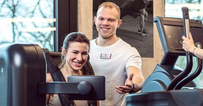 Auszubildender der BSA-Akademie weist Fitnessstudiomitglied in Fitnessgerät ein