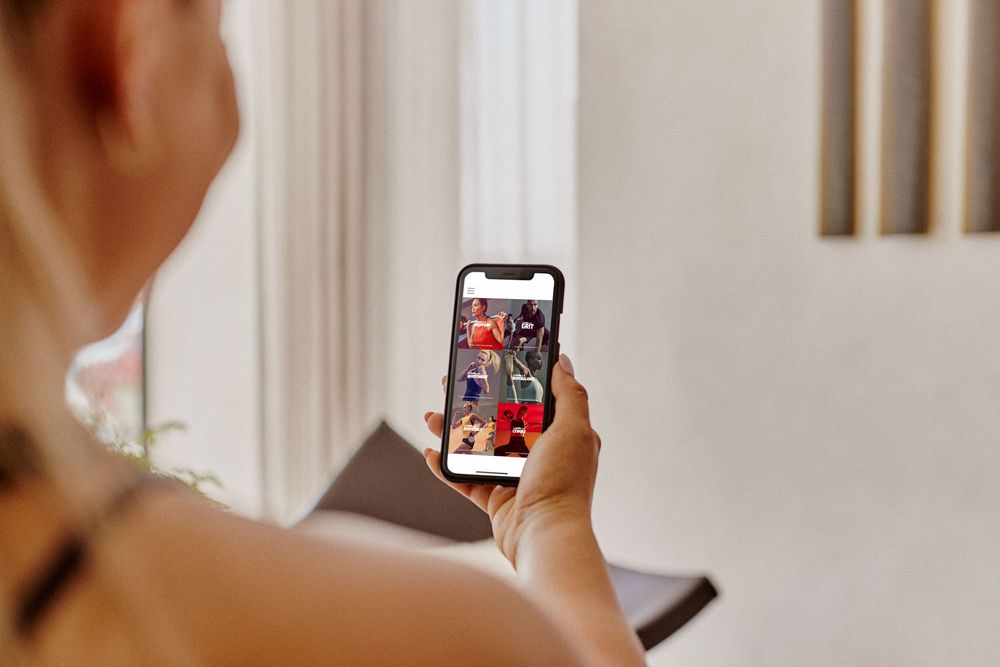Blick über die Schulter auf eine Fitnessapp mit verschiedenen Trainingsmöglichkeiten