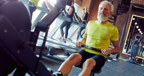 Älterer Mann trainiert am Rudergerät im Fitnessstudio