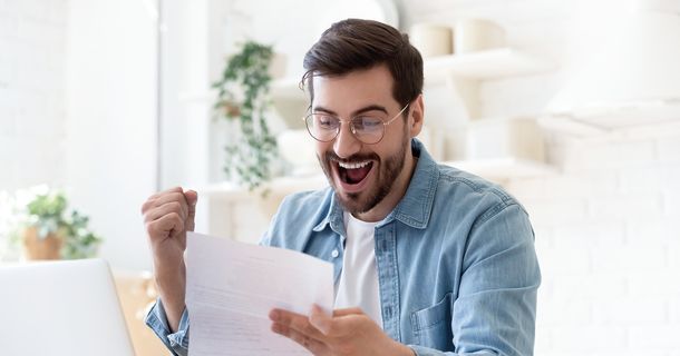 Mann freut sich während er sich ein Blatt Papier durchliest