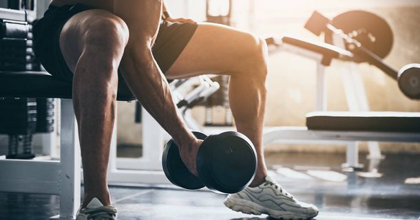 Mann trainiert sitzend mit einer Hantel