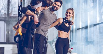 Junge Menschen im Fitnessstudio lachen und umarmen sich 