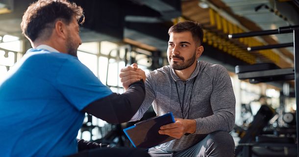 Trainer im Gym mit einem Mitglied