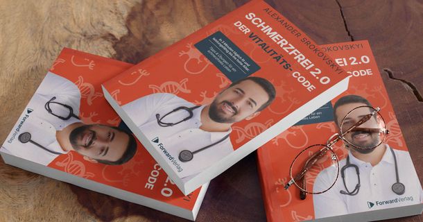 Alexander Srokovskyi posiert vor dem Cover seines zweiten Buchs Schmerzfrei 2.0