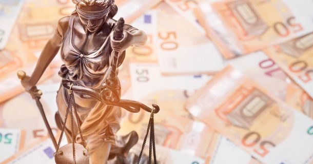 Eine kleine Bronzestatue der Justizia steht auf Geldscheinen