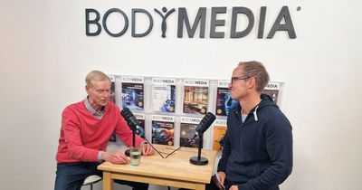Hubert Horn sitzt im BODYMEDIA Interview an einem erhöhtem Tisch mit zwei Mikrofonen. 
