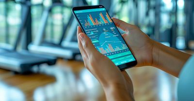 Trainer im Fitnessstudio hält Tablet in seiner Hand und prüft Zahlen