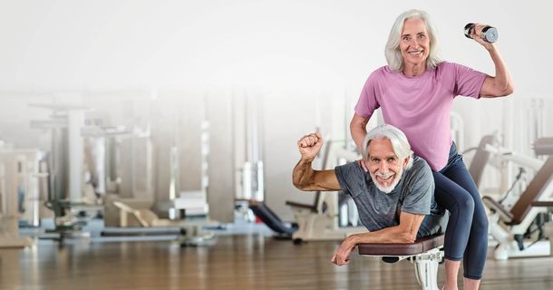 Älteres Paar beim Training im Fitnessstudio, lächeln in die Kamera