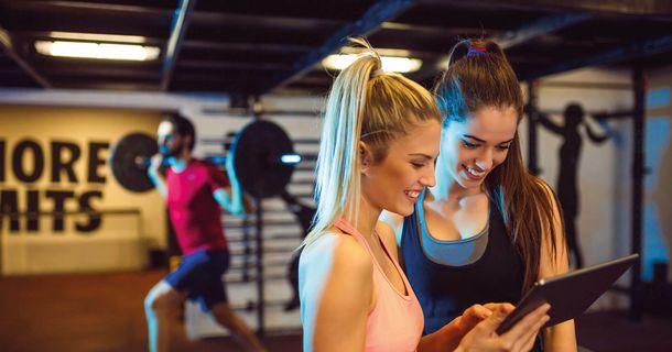 Zwei Frauen im Fitnessstudio schauen auf ein Tablet