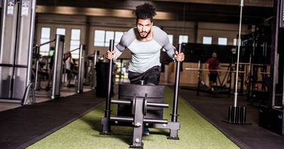 Mann schiebt einen Schlitten mit Gewicht in einem Fitnessstudio