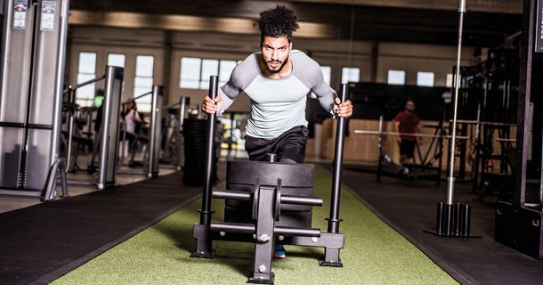 Mann schiebt einen Schlitten mit Gewicht in einem Fitnessstudio