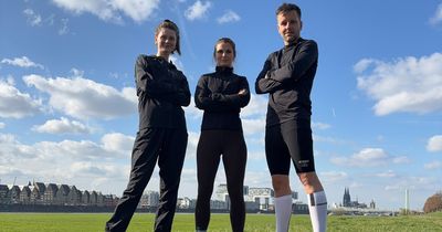 Zwei Frauen und ein Mann im Läufer-Outfit auf einer Wiese unter blauem Himmel