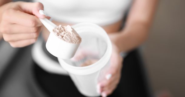 Fitnessstudiomitglied füllt Proteinpulver in ihren Shaker