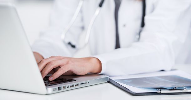 Ärztin schreibt am Laptop
