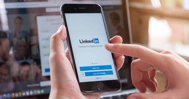 Person tippt etwas auf ein Smartphone ein, dass den LinkedIn Anmeldungsscreen geöffnet hat