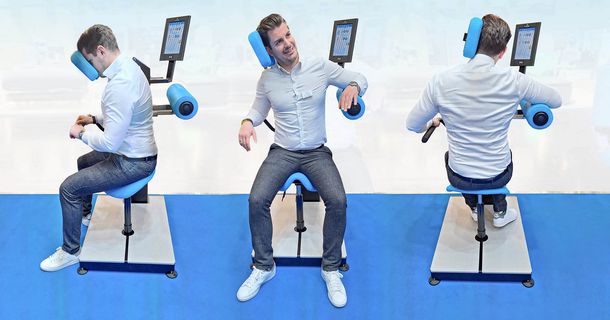 Junger Mann im Anzug  trainiert seinen Nacken am HUR Nackentrainer
