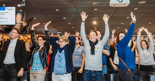 Teilnehmer des Swiss Coaching Day heben die Arme