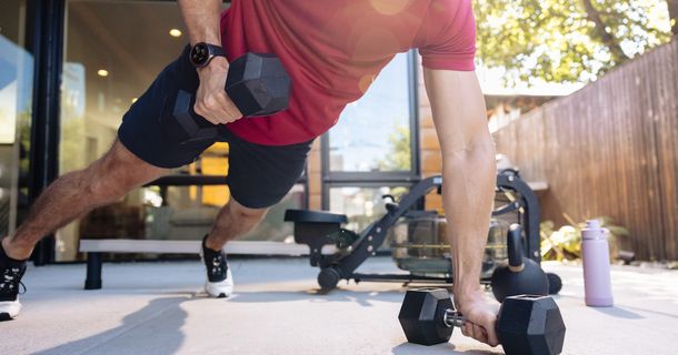 Mann mach Kraftübungen mit Hanteln und Amazfit-Uhr