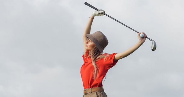 Frau mit Golfschläger in über den Kopf gestreckten Händen