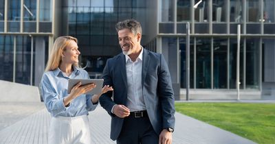 Ein Vorgesetzter läuft mit seiner Mitarbeiterin, die ein Tablett in der Hand hält.