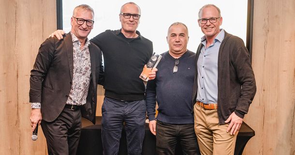 Vier Männer, einer davon mit dem Award in der Hand