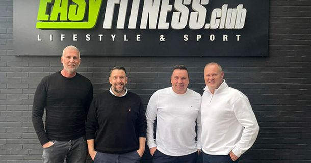 Michael Mäder, Michael Birk, David von Hase posieren vor dem EASYFITNESS-Logo nach dem Abschluss ihres Deals