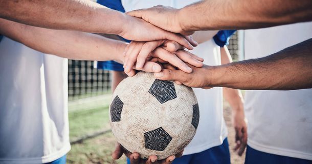 Fußball, Hände zusammen und Zusammenarbeit zur Unterstützung, Sport und Training im Stadion. Teamwork, Gruppengespräch und Fußballspieler mit Motivation für Bewegung, Trainingsziele und Erfolg im Wettkampf.